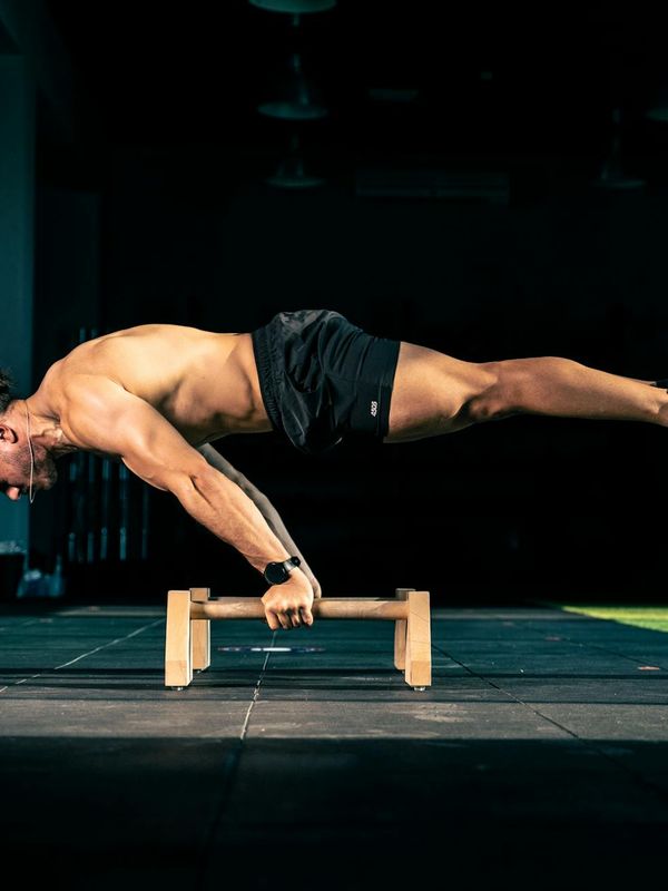 Man performing a controlled strength exercise in a minimalist dark room.